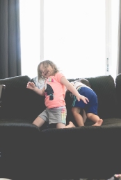 Two kids play and jump on the couch. Photo by VSD Photography